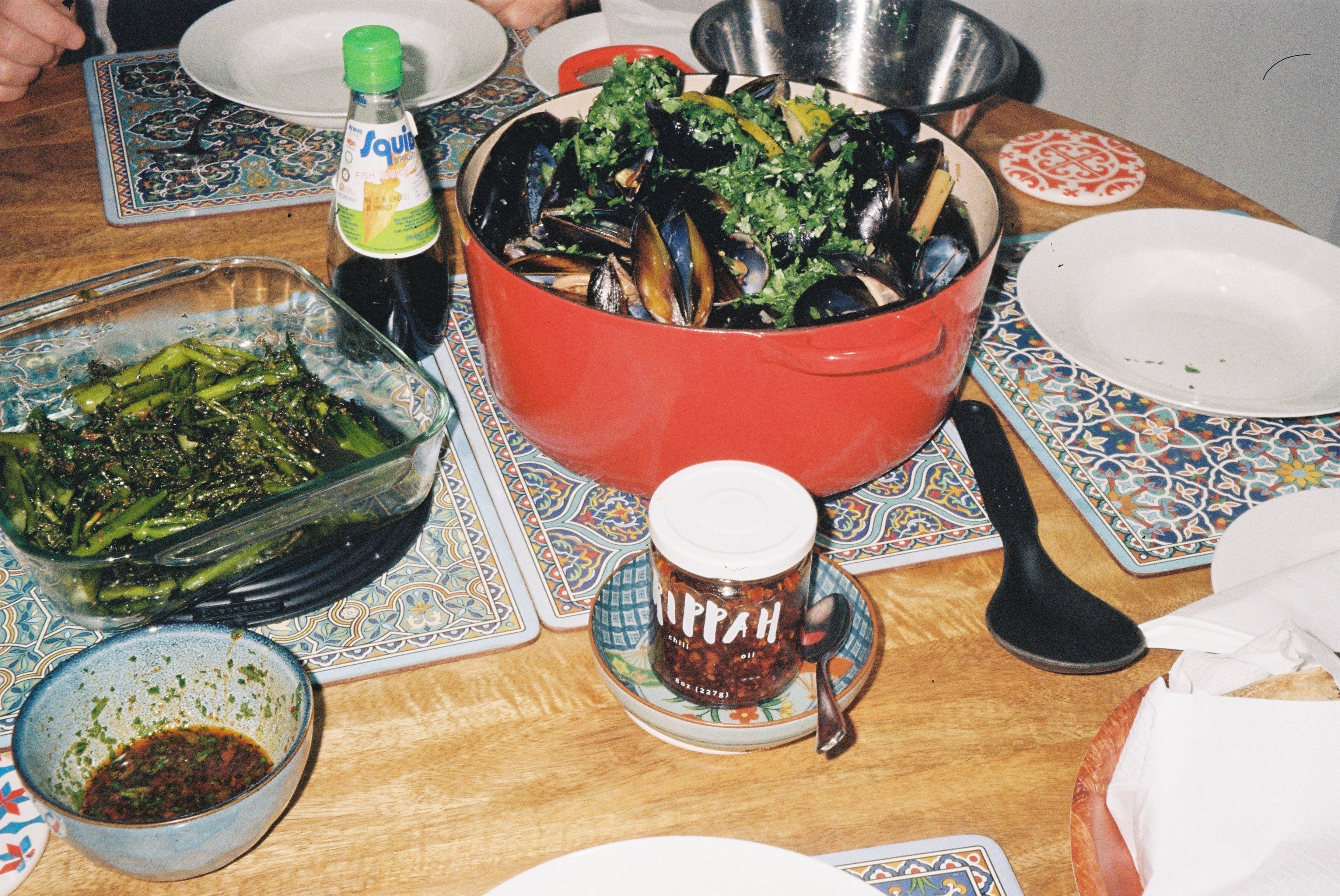 Thai coconut mussels in a black pot with Rippah Chili Oil, lemongrass, lime, and Thai basil — broth visible, shells open